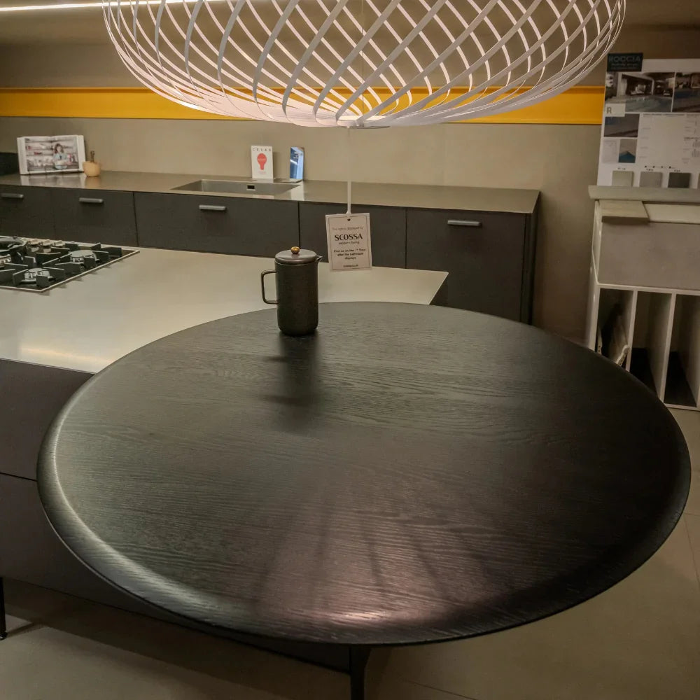 Round black table in a modern kitchen setting with a hanging light fixture.