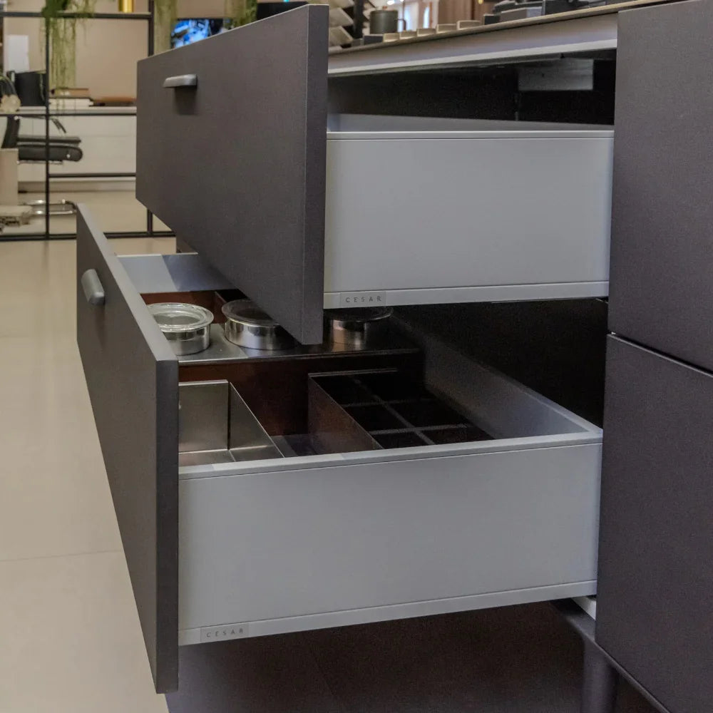 Open kitchen drawer with various compartments in a modern kitchen setting