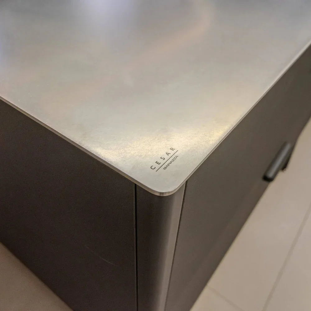 Close-up of a kitchen cabinet corner with 'Cesar' branding on a metallic surface.