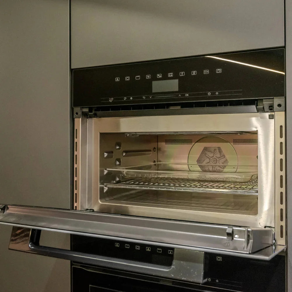 Stainless steel oven with open door showing interior racks and heating elements.