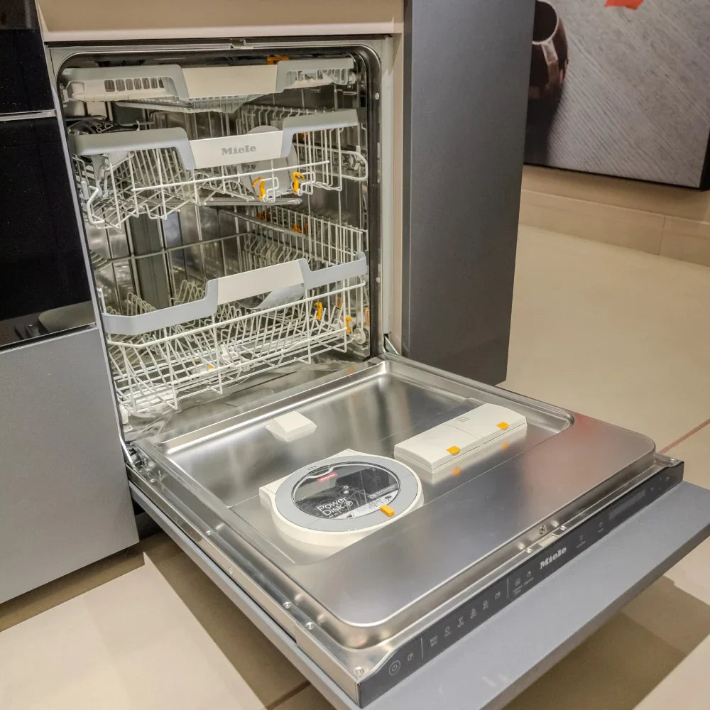 Open dishwasher with visible Miele branding in a kitchen setting