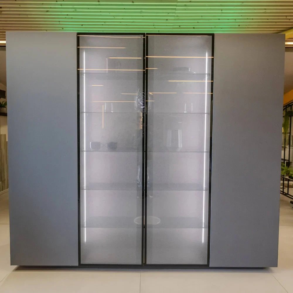 Modern glass door storage unit with metallic frame in a showroom setting