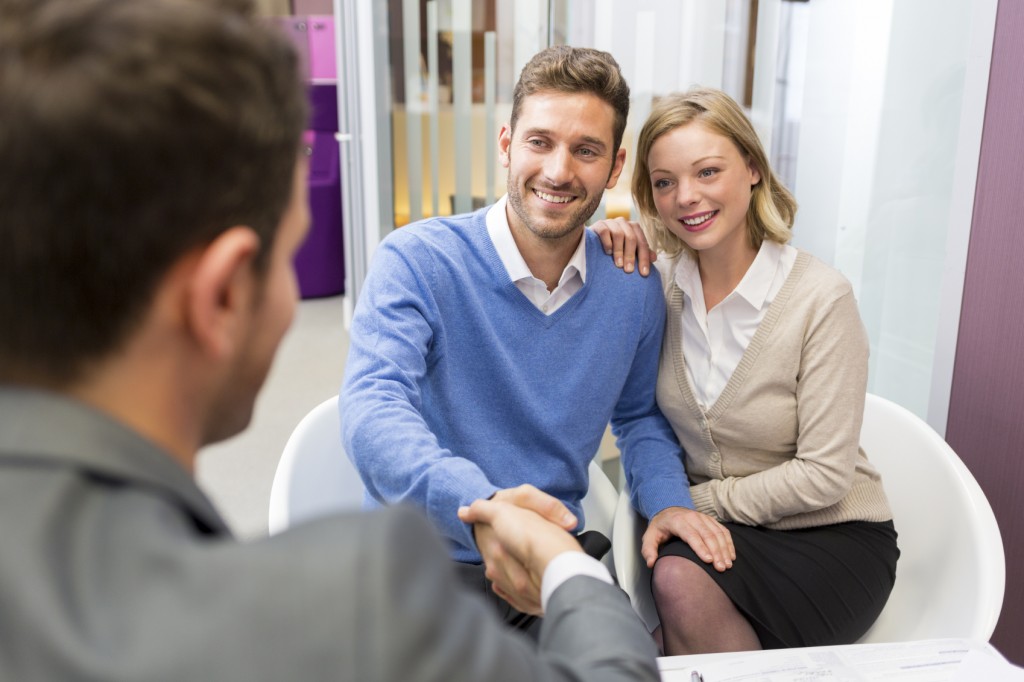 Young couple shaking hand real-estate agent in agency office