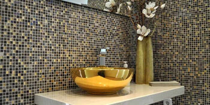 gold coloured sink with dark themed tiles
