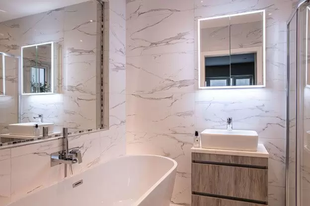 Beautiful modern bathroom with marble tiles and mirrored vanity unit 