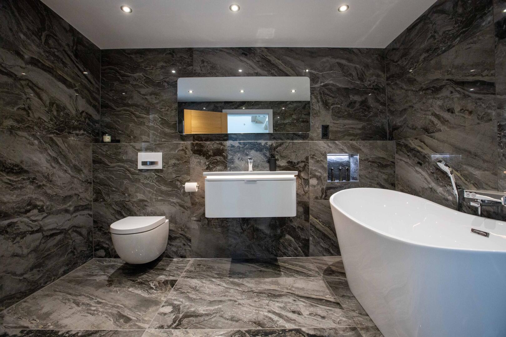 Beautiful grey marble bathroom with large rectangular mirror and spotlights