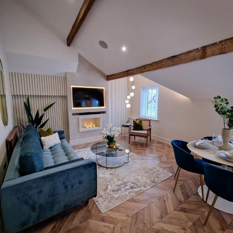 cosy living room with wood floor, wood beams, blue couch and plants around